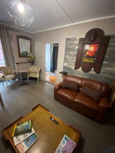 a living room with a leather couch and a table at COSY B&B in Murat