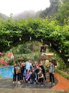 un grupo de personas posando para una foto bajo un arco en Tam Coc Rice Fields Resort, en Ninh Binh