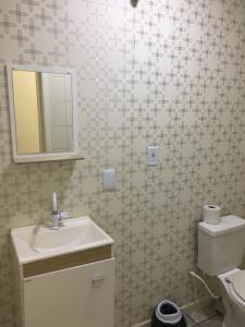 uma casa de banho com um lavatório, um espelho e um WC. em Loft confortável no Centro em Chapecó