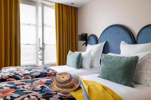 a hotel room with two beds and a hat on the bed at Hôtel Maxim Opéra in Paris