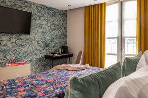 a bedroom with a bed and a tv on the wall at H&ocirc;tel Maxim Op&eacute;ra in Paris