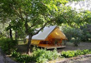 una tienda amarilla con una mesa bajo un árbol en Camping Karavomilos en Sami