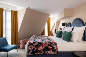 een hotelkamer met een bed en een stoel bij Hôtel Maxim Opéra in Parijs