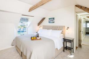 a white bedroom with a large bed with a tray on it at White House, Port Isaac Bay Holidays in Port Isaac