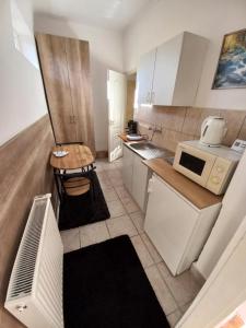 een kleine keuken met witte kasten en een magnetron bij Aquatherma Apartman in Sárospatak
