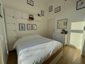 a bedroom with a white bed and pictures on the wall at Mon refuge magique à Disneyland in Chanteloup-en-Brie