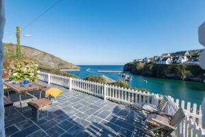 a patio with a table and chairs and the ocean at White House, Port Isaac Bay Holidays in Port Isaac