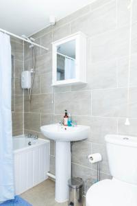 a bathroom with a sink and a toilet and a tub at 2ndHomeStays-West Bromwich- A Charming 2-Bedroom Maisonette in West-Midlands, Suitable for long Stay Contractors-Families-Group of Friends on Holiday, 10 mins to J1 M5 and 24 mins to Birmingham in West Bromwich