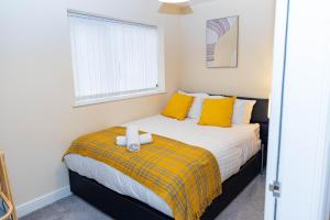 a bedroom with a bed with yellow pillows at 2ndHomeStays-West Bromwich- A Charming 2-Bedroom Maisonette in West-Midlands, Suitable for long Stay Contractors-Families-Group of Friends on Holiday, 10 mins to J1 M5 and 24 mins to Birmingham in West Bromwich