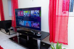 a flat screen tv sitting on a stand with red curtains at 2ndHomeStays-West Bromwich- A Charming 2-Bedroom Maisonette in West-Midlands, Suitable for long Stay Contractors-Families-Group of Friends on Holiday, 10 mins to J1 M5 and 24 mins to Birmingham in West Bromwich