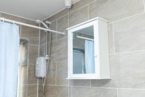 a bathroom with a shower with a mirror and a cabinet at 2ndHomeStays-West Bromwich- A Charming 2-Bedroom Maisonette in West-Midlands, Suitable for long Stay Contractors-Families-Group of Friends on Holiday, 10 mins to J1 M5 and 24 mins to Birmingham in West Bromwich