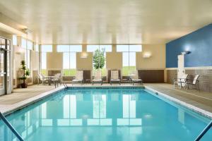 a pool in a hotel room with chairs and tables at Hyatt House Denver Airport in Denver