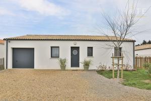 a white house with a garage at Élégante maison avec piscine in Saint-Vincent-sur-Jard