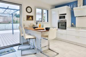 een keuken met witte kasten en een tafel en stoelen bij Élégante maison avec piscine in Saint-Vincent-sur-Jard
