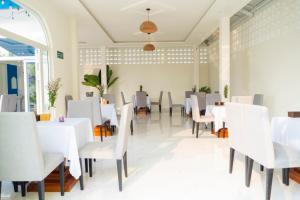 uma sala de jantar com mesas e cadeiras brancas em Nhật Hạ Villa em Tam Hà
