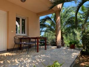 een tafel en stoelen op een patio met een palmboom bij Grand Pool Apartment Ika-Opatija in Opatija