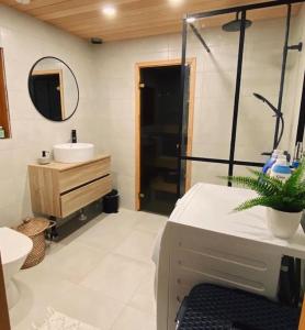 a bathroom with a sink and a toilet and a mirror at Upea villa lähellä rantaa poreallas & SUP-laudat in Vaasa