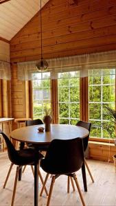 comedor con mesa, sillas y ventanas en Upea villa lähellä rantaa poreallas & SUP-laudat, en Vaasa