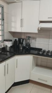 uma cozinha com armários brancos e bancadas pretas em Casa no Country em Cascavel