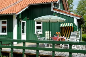 uma casa verde e branca com cadeiras e um guarda-sol em Sommerhaus am Meer em Barsfleth