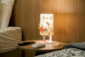 una lámpara de bienvenida en una mesa junto a una cama en Trento Hotel Guaíra by Unna en Guaíra