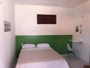 een groene en witte slaapkamer met een bed en een stoel bij Casa e suítes da Vava in Trairi