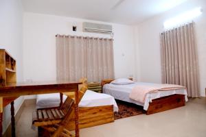 a bedroom with a bed and a table and a desk at Nirapod Holiday Home in Sylhet