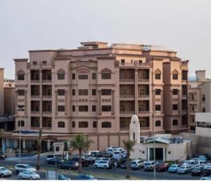 فندق كارم الخبر - Karim Hotel Khobar في الخبر: مبنى كبير به سيارات تقف في موقف للسيارات