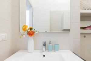 uma casa de banho branca com um vaso com flores num lavatório em Charming Milanese Aparment em Milão
