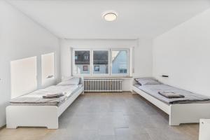 two beds in a white room with a window at MONTEURWOHNUNG Ebersbach EB03 RAUMSCHMIDE Apartments in Ebersbach an der Fils