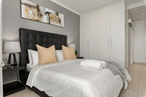 a bedroom with a large bed with a black headboard at Portico in Bloubergstrand