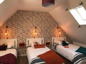 Longues-sur-MerにあるGrand gîte de la Ferme De La Tourelleのベッド2台と壁が備わる屋根裏部屋です。