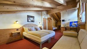 een slaapkamer met een bed en een bank in een kamer bij Albergo Alpenrose in Livigno
