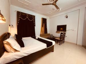Hotel 4 You - Top Rated and Most Awarded Property In Rishikesh في ريشيكيش: غرفة نوم بسرير ومكتب وتلفزيون