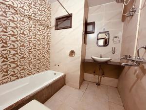 Hotel 4 You - Top Rated and Most Awarded Property In Rishikesh في ريشيكيش: حمام مع حوض ومغسلة وحوض استحمام
