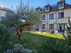 a large building with a tree in front of it at Villa d'exception, 5 chambres, 20m plage, spa. in Bénerville-sur-Mer