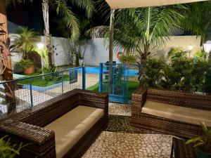 a patio with wicker benches and a swimming pool at Pousada Cambará Suítes in Bonito