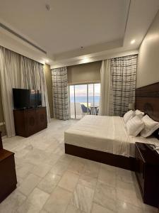 1 dormitorio con 1 cama grande y TV. en Vista Haql Hotel en Al Humaizah