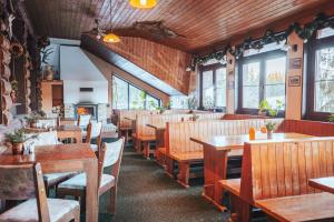 a restaurant with wooden tables and chairs and windows at Myslivna Harrachov in Harrachov