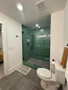 a bathroom with a toilet and a shower with green tiles at Closetobroadwayairportoprymillsgameroom in Nashville