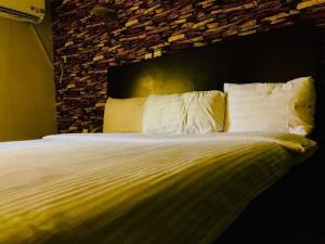 ein Bett mit weißen Kissen und einer Steinmauer in der Unterkunft BELIANA SUITES in Uyo
