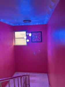 a pink room with a purple wall and a window at BELIANA SUITES in Uyo