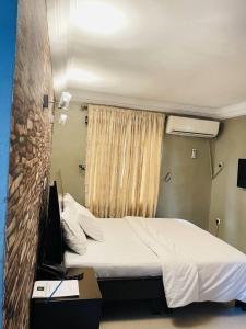 a bedroom with a bed and a desk and a window at BELIANA SUITES in Uyo