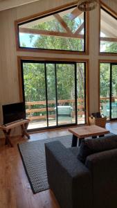 uma sala de estar com um sofá, uma mesa e janelas em Tres Bosques em Pucón