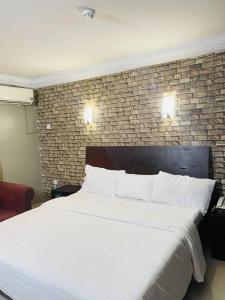 a bedroom with a large white bed with a brick wall at BELIANA SUITES in Uyo