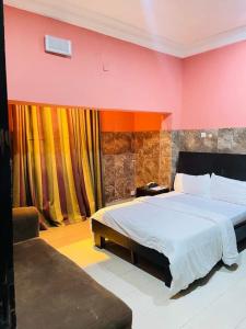 ein Schlafzimmer mit einem großen Bett und einer roten Wand in der Unterkunft BELIANA SUITES in Uyo