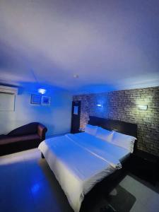 a bedroom with a large white bed with a brick wall at BELIANA SUITES in Uyo