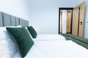 a bedroom with two white beds with green pillows at Slow River Apartment in Nowe Miasto Lubawskie