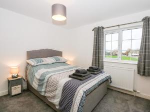 a bedroom with a bed and a window at Red Brick Cottage in Alford