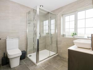 a bathroom with a shower and a toilet and a sink at Red Brick Cottage in Alford